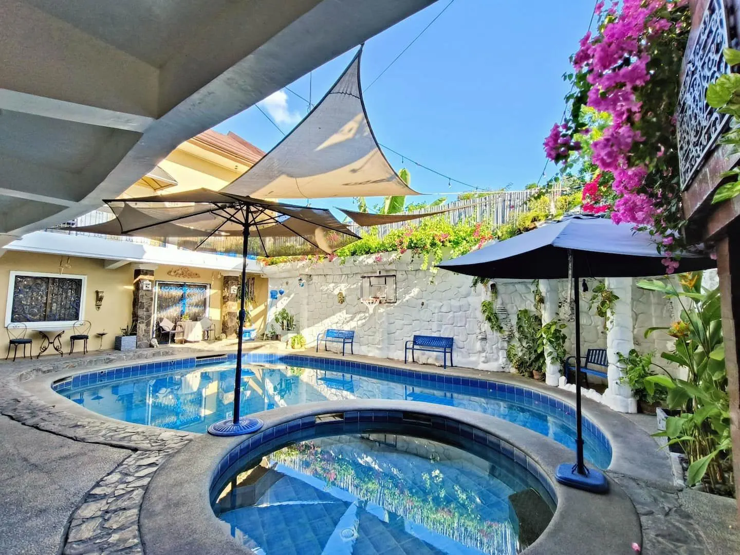 The adult hot spring pool and round kiddie pool by day, under shade sails and pink bougainvillea